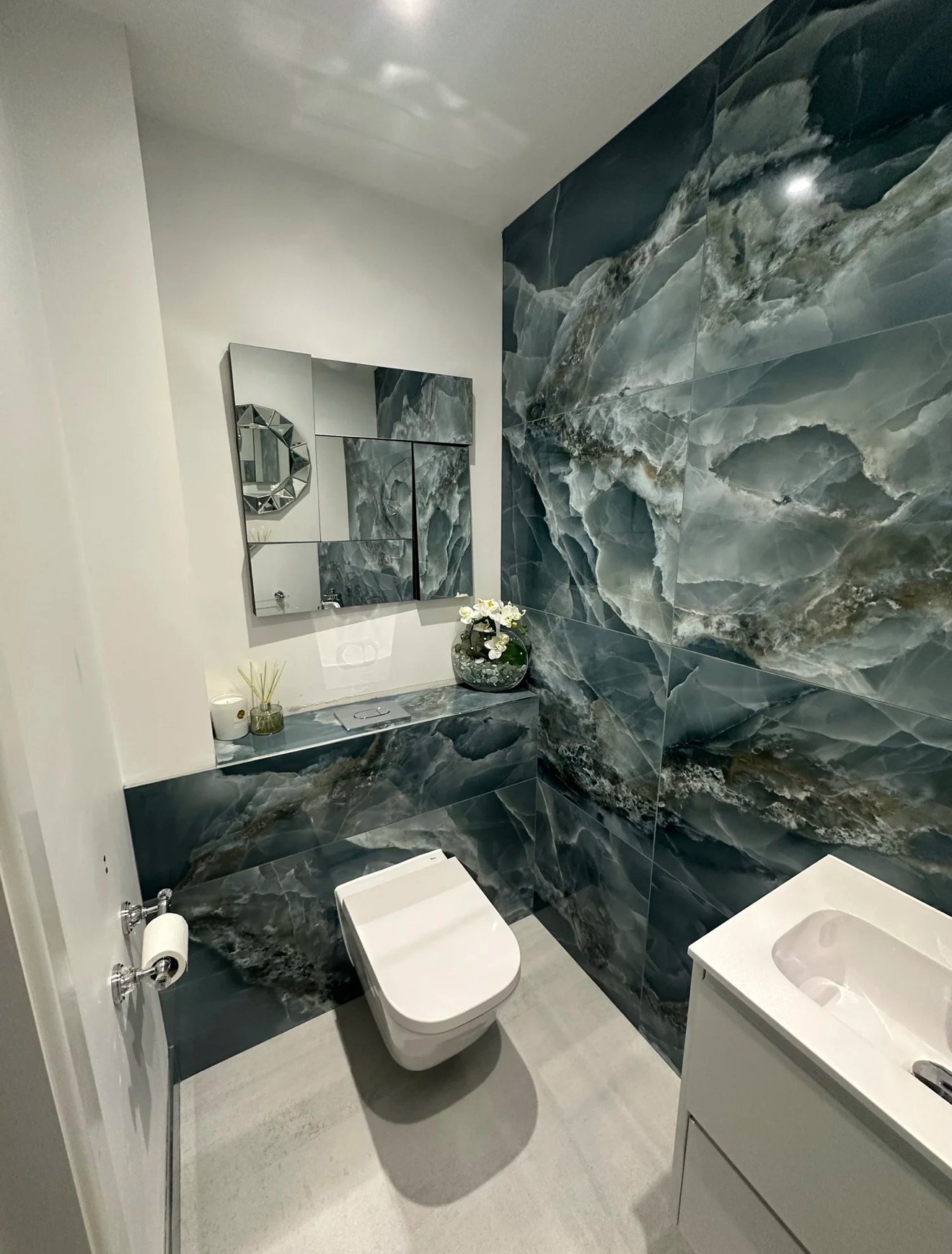 Cloakroom with dramatic blue onyx-effect tiles and wall-hung toilet