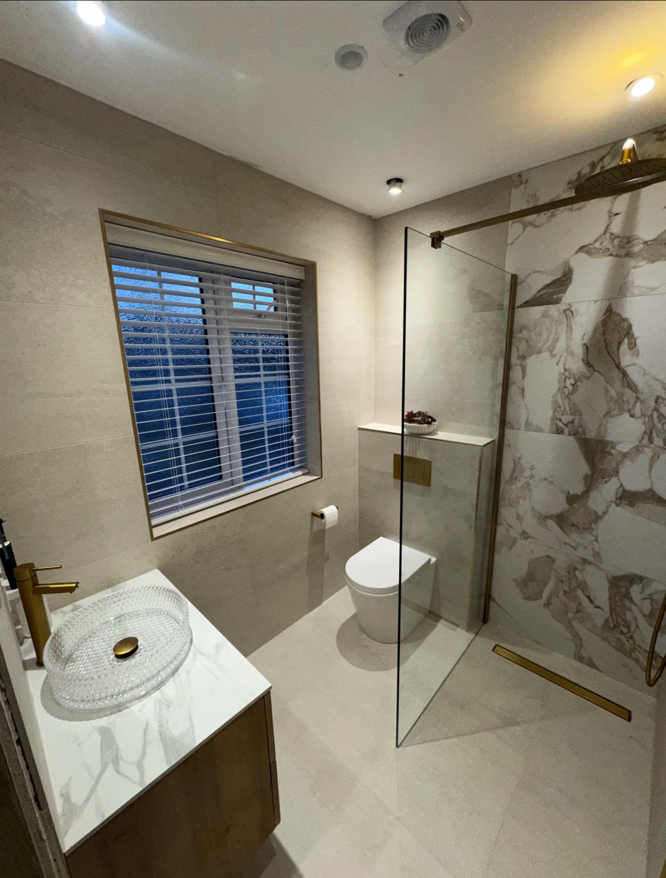 Contemporary walk-in shower room with marble feature wall and brass fittings