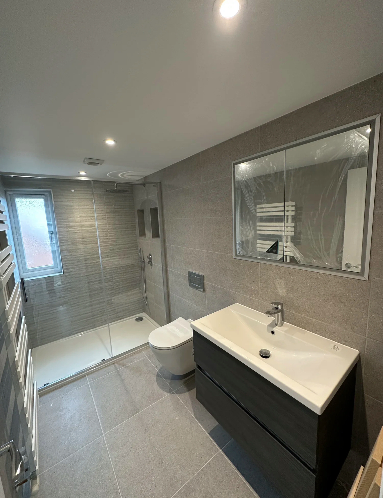 Grey-tiled shower room with walk-in enclosure and floating vanity