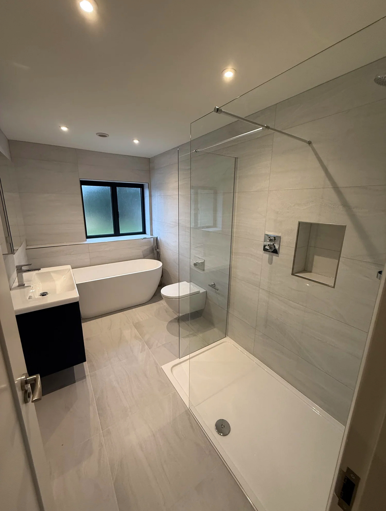 Modern family bathroom with walk-in shower, freestanding bath and black vanity